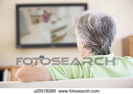 Man watching television using remote control View Large Photo Image Stock Image - Man watching television using remote control. Fotosearch