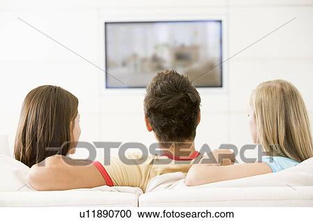 Stock Image - Three friends in living room watching television. Fotosearch