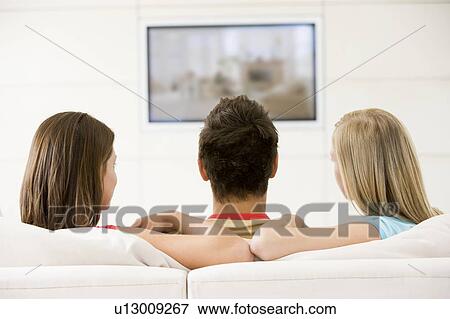 Stock Photo - Three friends in living room watching television. Fotosearch
