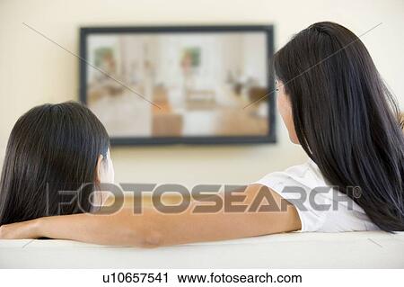 Stock Image - Woman and young girl in living room with flat screen television. Fotosearch