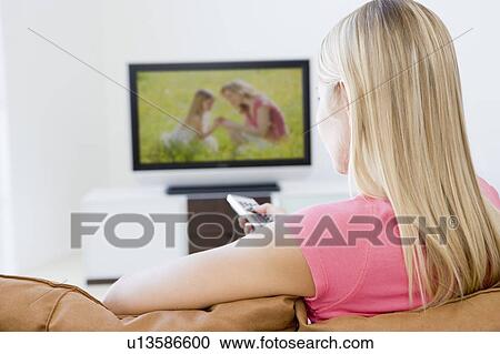 Stock Image - Woman in living room watching television. Fotosearch