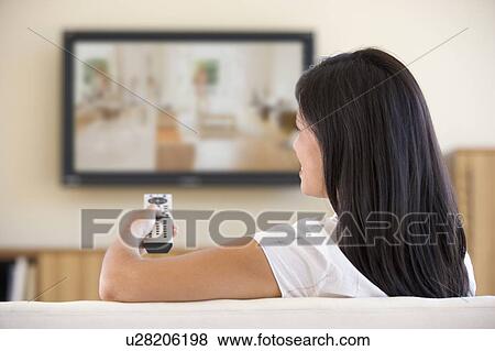 Stock Photo - Woman in living room watching television. Fotosearch