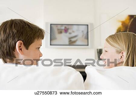 Stock Image - Young boy and young girl in living room with flat screen television. Fotosearch