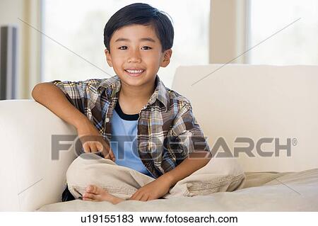 Stock Image - Young boy in living room smiling. Fotosearch