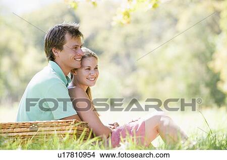 Picture - Couple at park having a picnic and smiling. Fotosearch