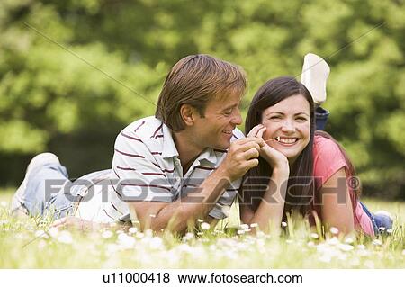 Couple lying outdoors with flower smiling View Large Photo Image Stock Photo - Couple lying outdoors with flower smiling. Fotosearch