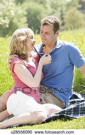 Couple sitting outdoors holding flower smiling View Large Photo Image Stock Image - Couple sitting outdoors holding flower smiling. Fotosearch