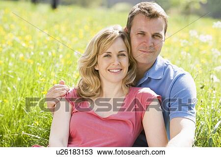 Stock Image - Couple sitting outdoors smiling. Fotosearch