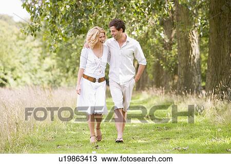 Stock Image - Couple walking on path smiling. Fotosearch