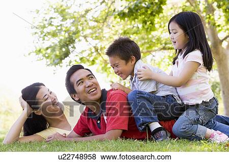 Family lying outdoors being playful and smiling View Large Photo Image Stock Photo - Family lying outdoors being playful and smiling. Fotosearch