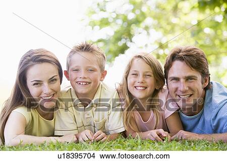 Picture - Family lying outdoors smiling. Fotosearch