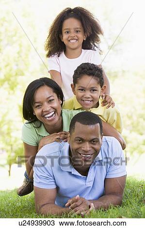 Stock Image - Family lying outdoors smiling. Fotosearch