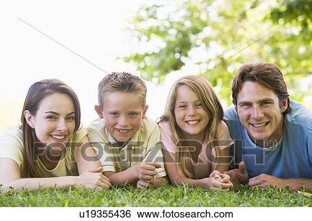Stock Photograph - Family lying outdoors smiling. Fotosearch