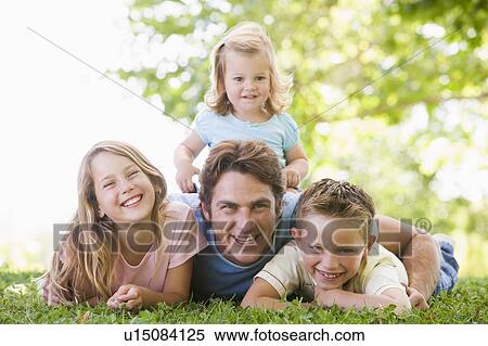 Stock Photography - Family lying outdoors smiling. Fotosearch