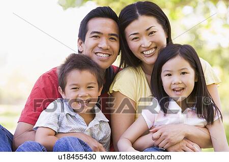 Stock Image - Family sitting outdoors smiling. Fotosearch