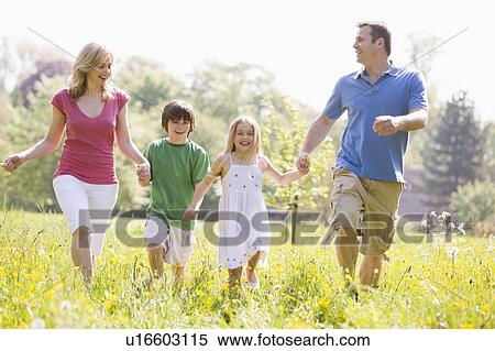 Stock Photography - Family walking outdoors holding hands smiling. Fotosearch