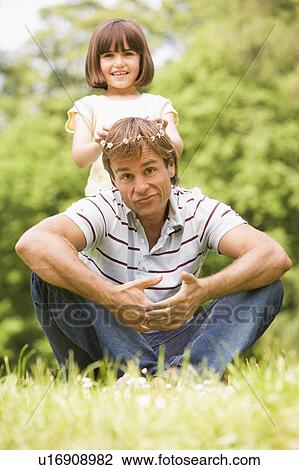 Stock Image - Father and daughter sitting outdoors with flowers smiling. Fotosearch