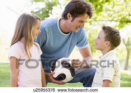 Man and two young children outdoors holding volleyball and smiling View Large Photo Image Stock Photograph - Man and two young children outdoors holding volleyball and smiling. Fotosearch