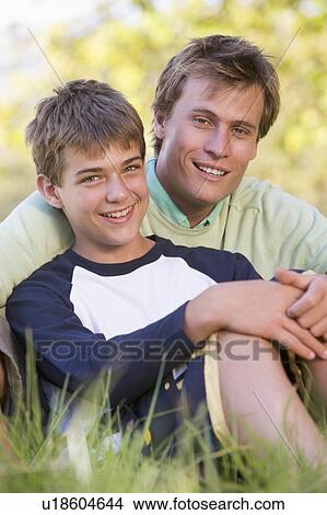 Man and young boy sitting outdoors smiling View Large Photo Image Picture - Man and young boy sitting outdoors smiling. Fotosearch