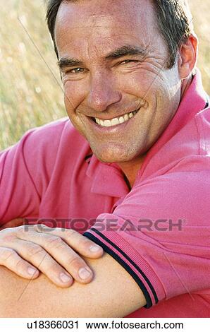Stock Image - Man sitting outdoors smiling. Fotosearch