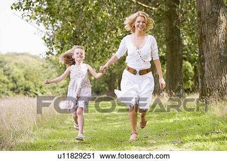 Mother and daughter walking on path holding hands smiling View Large Photo Image Stock Image - Mother and daughter walking on path holding hands smiling. Fotosearch