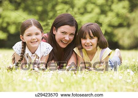 Mother and daughters lying outdoors with flower smiling View Large Photo Image Stock Image - Mother and daughters lying outdoors with flower smiling. Fotosearch