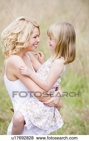 Stock Photo - Mother holding daughter outdoors smiling. Fotosearch