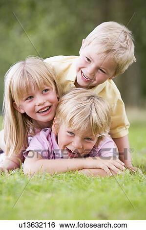 Three young children playing outdoors smiling View Large Photo Image Stock Photograph - Three young children playing outdoors smiling. Fotosearch