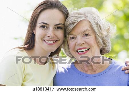 Two women outdoors embracing and smiling View Large Photo Image Stock Photo - Two women outdoors embracing and smiling. Fotosearch