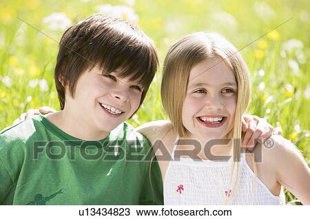 Two young children sitting outdoors arm in arm smiling View Large Photo Image Stock Image - Two young children sitting outdoors arm in arm smiling. Fotosearch