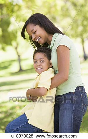 Woman and young boy outdoors embracing and smiling View Large Photo Image Stock Photo - Woman and young boy outdoors embracing and smiling. Fotosearch