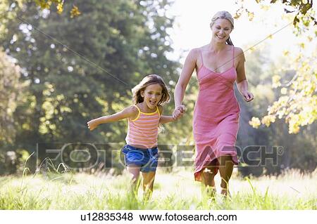 Woman and young girl running outdoors holding hands and smiling View Large Photo Image Stock Photo - Woman and young girl running outdoors holding hands and smiling. Fotosearch