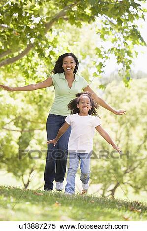 Stock Photography - Woman and young girl running outdoors smiling. Fotosearch