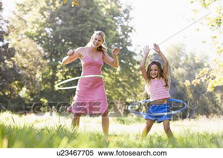 Woman and young girl with hula hoops outdoors smiling View Large Photo Image Stock Photography - Woman and young girl with hula hoops outdoors smiling. Fotosearch