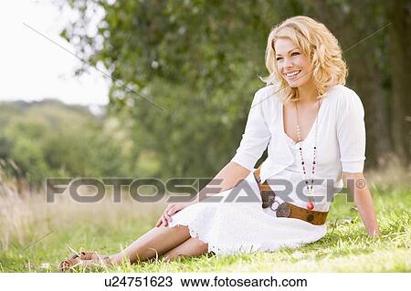 Stock Image - Woman sitting outdoors smiling. Fotosearch