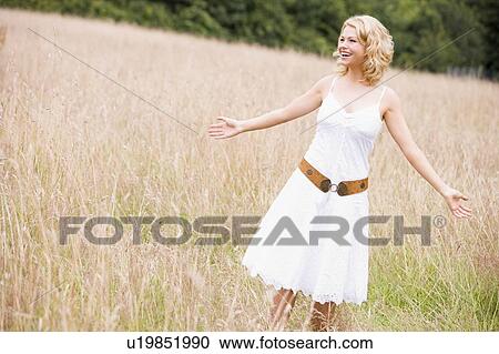 Stock Image - Woman standing outdoors smiling. Fotosearch