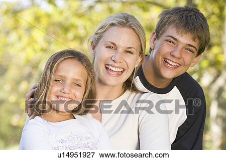 Stock Photo - Woman with two young children outdoors smiling. Fotosearch