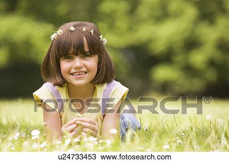 Young girl lying outdoors with flowers smiling View Large Photo Image Stock Image - Young girl lying outdoors with flowers smiling. Fotosearch