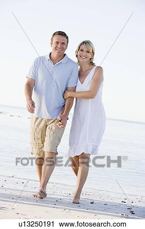 Couple at the beach holding hands and smiling View Large Photo Image Stock Image - Couple at the beach holding hands and smiling. Fotosearch