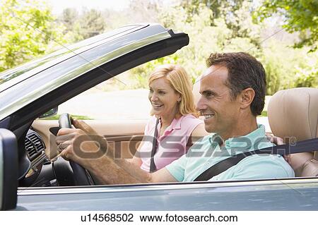 Stock Image - Couple in convertible car smiling. Fotosearch
