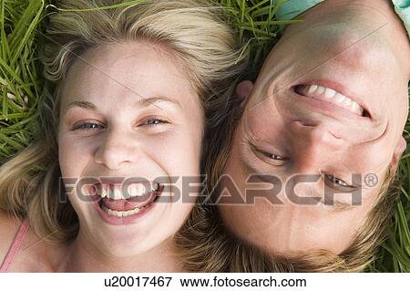 Stock Photo - Couple lying in grass smiling. Fotosearch