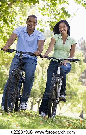 Couple on bikes outdoors smiling View Large Photo Image Stock Photo - Couple on bikes outdoors smiling. Fotosearch