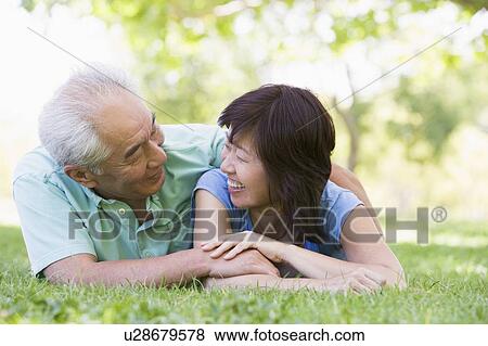 Couple relaxing outdoors in park smiling View Large Photo Image Stock Photo - Couple relaxing outdoors in park smiling. Fotosearch