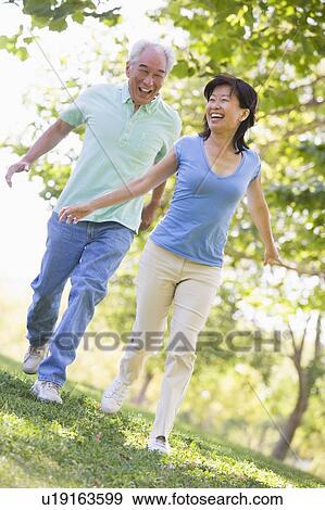 Couple running outdoors in park by lake smiling View Large Photo Image Stock Photo - Couple running outdoors in park by lake smiling. Fotosearch