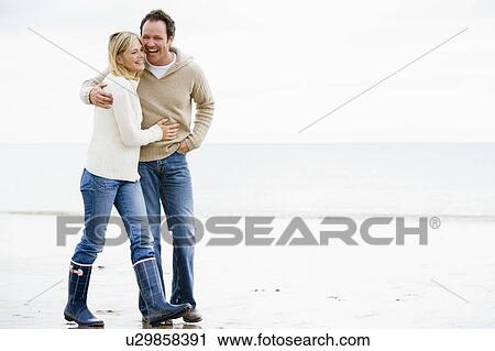 Couple walking on beach arm in arm smiling View Large Photo Image Stock Image - Couple walking on beach arm in arm smiling. Fotosearch