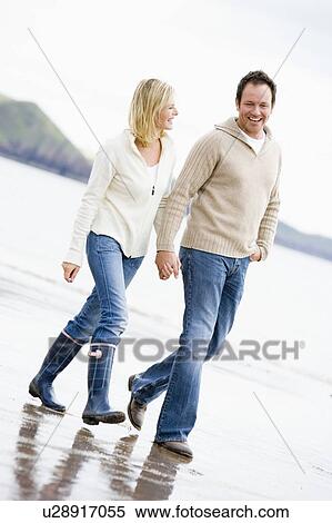 Couple walking on beach holding hands smiling View Large Photo Image Stock Photography - Couple walking on beach holding hands smiling. Fotosearch