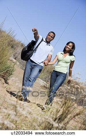 Picture - Couple walking on path holding hands and smiling. Fotosearch