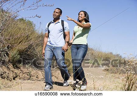 Couple walking on path holding hands and smiling View Large Photo Image Stock Photo - Couple walking on path holding hands and smiling. Fotosearch