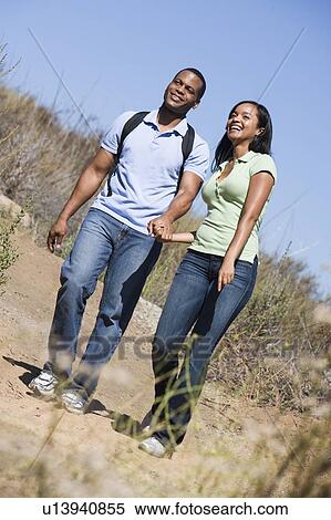 Couple walking on path holding hands and smiling View Large Photo Image Stock Photography - Couple walking on path holding hands and smiling. Fotosearch