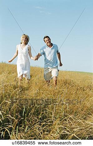 Stock Photography - Couple walking outdoors holding hands smiling. Fotosearch